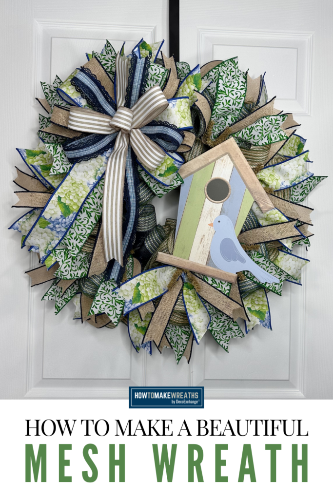 Spring mesh wreath with birdhouse sign and layered bow made with hydrangea ribbon and burlap ribbon on a white door.