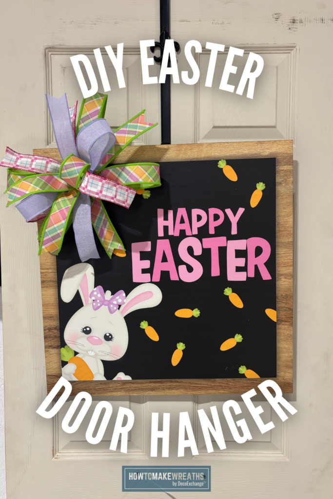 DIY Easter door hanger featuring a black square sign with pink Happy Easter lettering, scattered orange carrots, a white bunny in the corner, and a pastel plaid ribbon bow hanging on a cream-colored door.