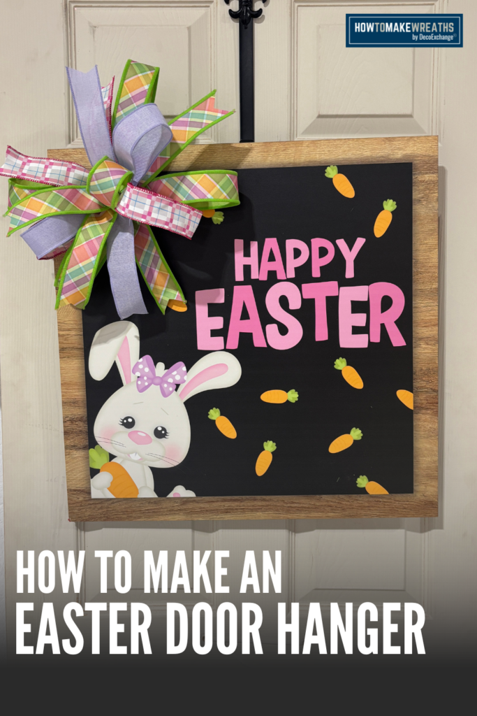 Handmade Easter door hanger with a large pastel plaid bow, lavender ribbon tails, pink Happy Easter text, small orange carrots, and a bunny illustration attached to a wood-framed sign.