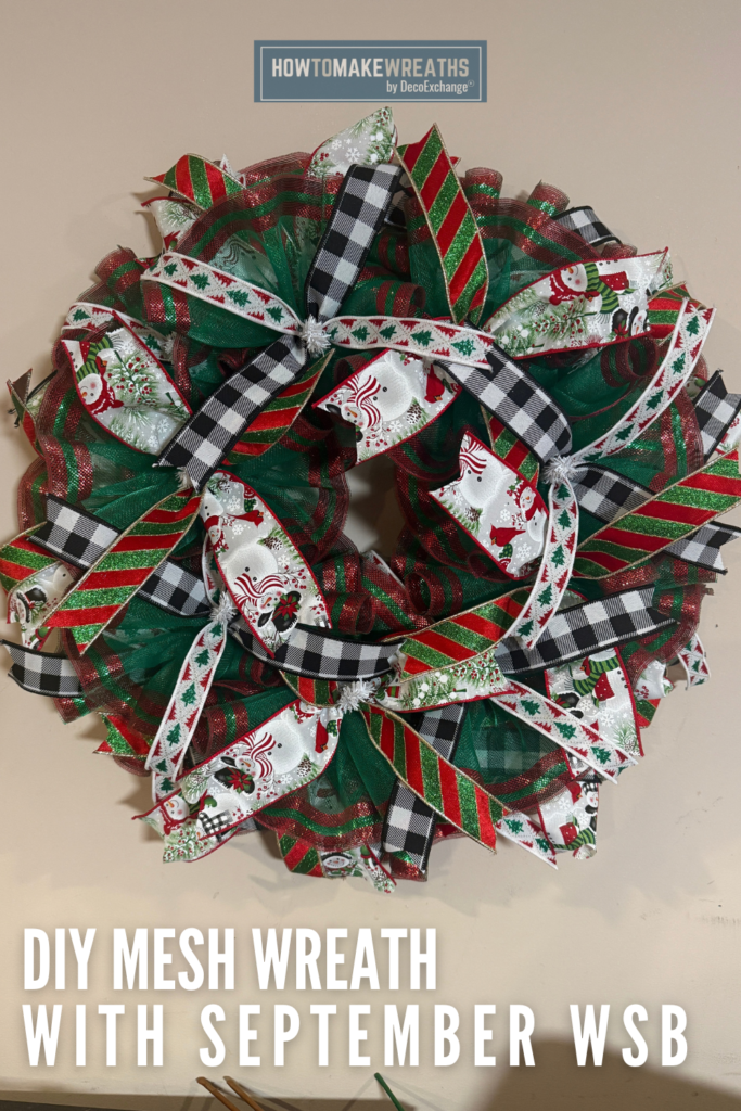 Red and green Christmas deco mesh wreath with snowman print ribbon, black and white buffalo check ribbon, red and green glitter striped ribbon, and white Christmas tree ribbon, with text that reads DIY Mesh Wreath with September WSB
